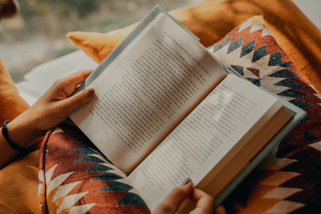 Persona leyendo un libro con postura correcta en sillón, con soporte lumbar y libro elevado