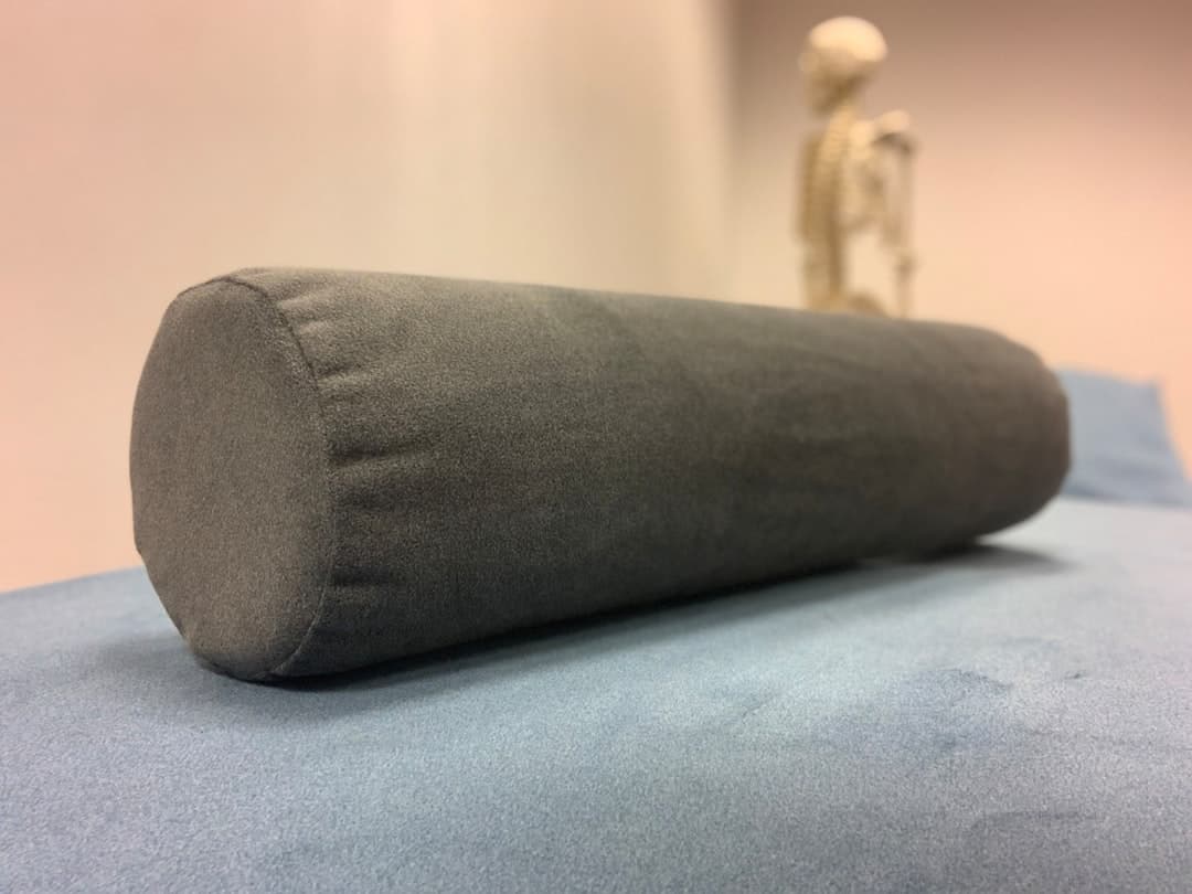 Almohada cervical contorneada de viscoelástica sobre una cama con funda blanca
