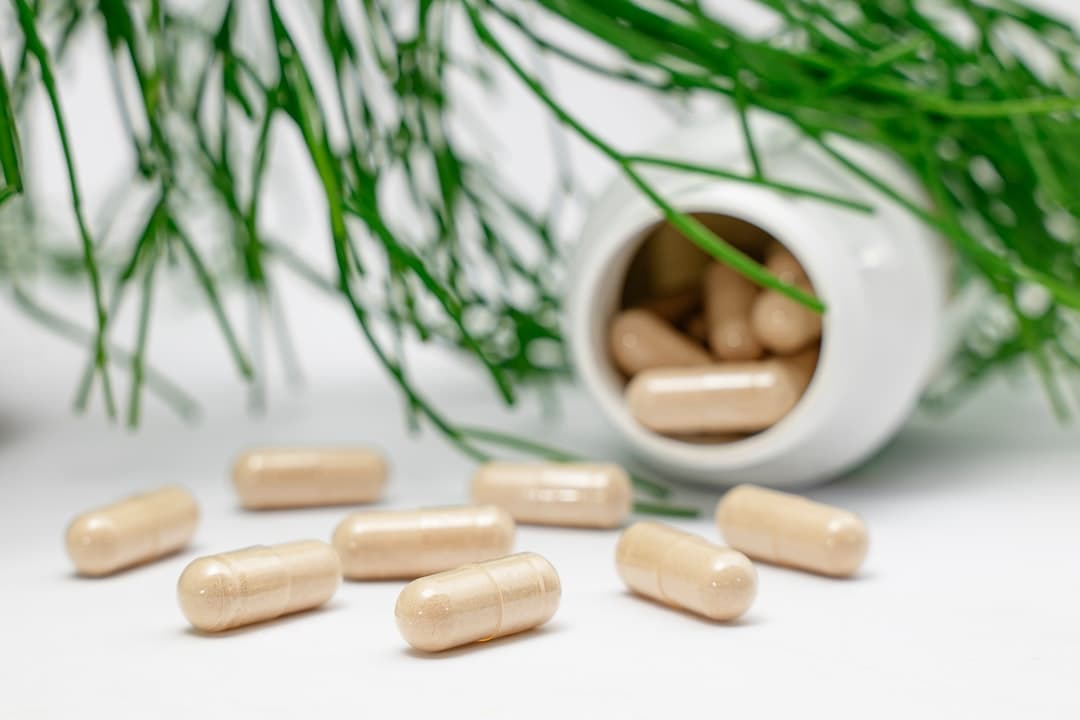 Variedad de suplementos en cápsulas y frascos junto a alimentos naturales sobre una superficie de madera