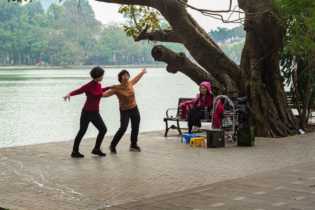 Grupo de personas mayores practicando Tai Chi al aire libre en un parque, postura de movimiento suave