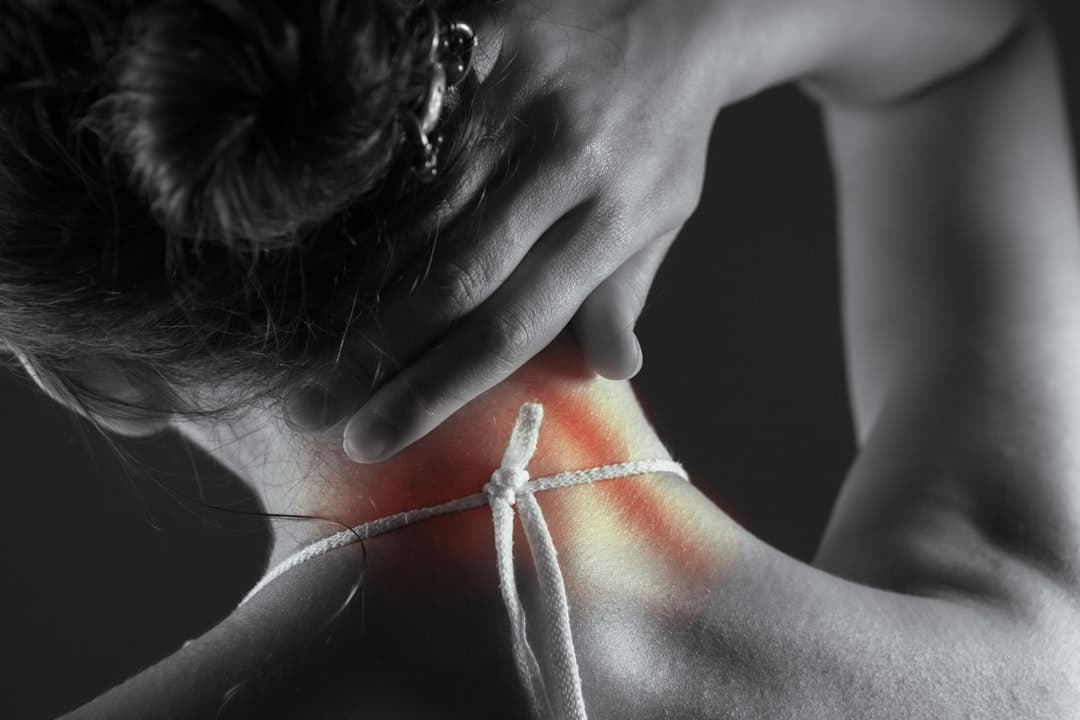 Persona aplicando calor con una almohadilla eléctrica en el cuello para aliviar una contractura cervical