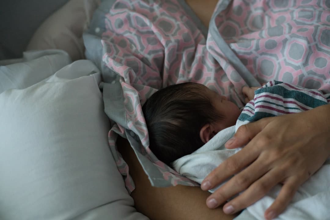 Madre reciente realizando ejercicios suaves de suelo pélvico en una esterilla mientras el bebé duerme cerca