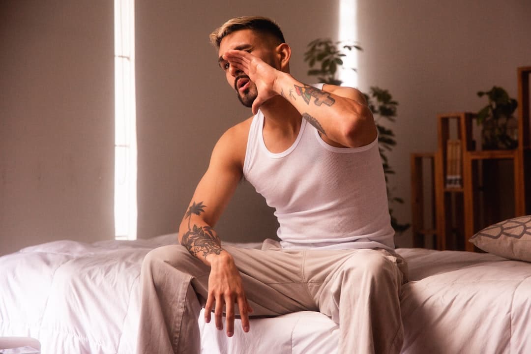 Persona sentada en el borde de la cama llevándose la mano a la zona lumbar al despertar